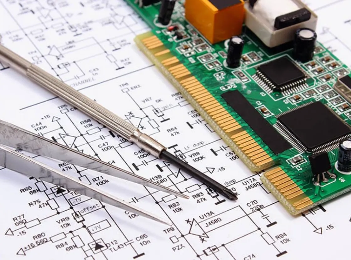 Circuit board on top of a printed schematic with tweezers