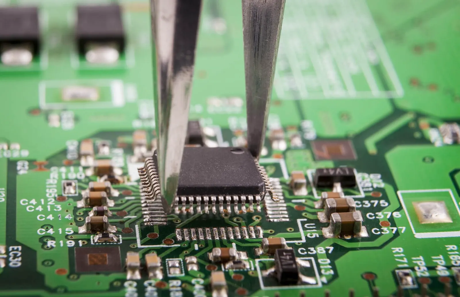 Chip being placed on a circuit board with tweezers