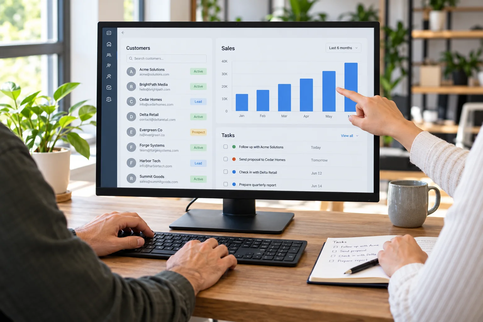 Two colleagues reviewing customer records and sales reports in business software